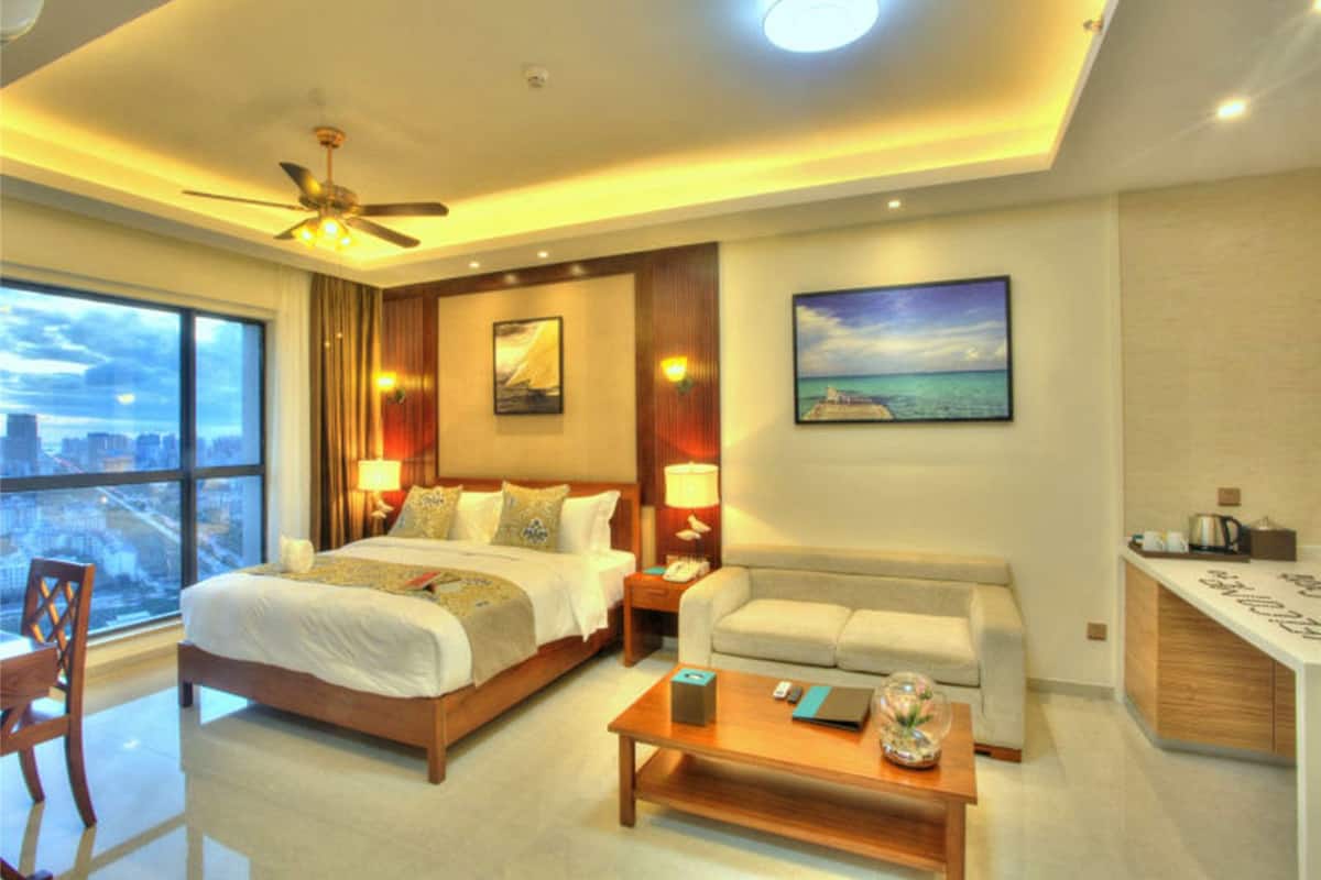 Habitación de hotel con una cama grande, un sofá, un escritorio y vistas a la ciudad.