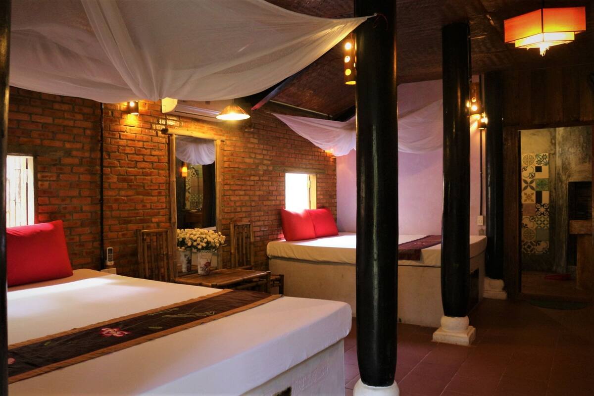 Ein Hotelzimmer mit zwei Betten, einer Ziegelwand, einem Holzboden und einem großen Fenster.