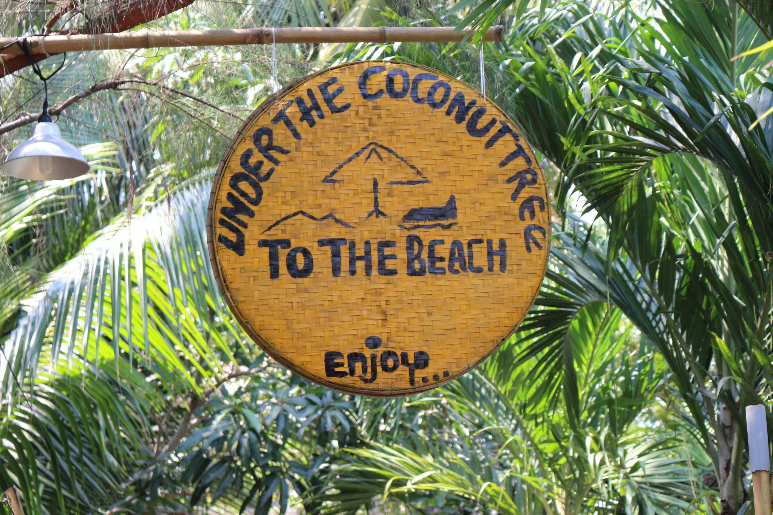 Ein rundes Schild mit dem Text: „LIMBER DER COCONUT TREE ZUM STRAND GENIESSEN.