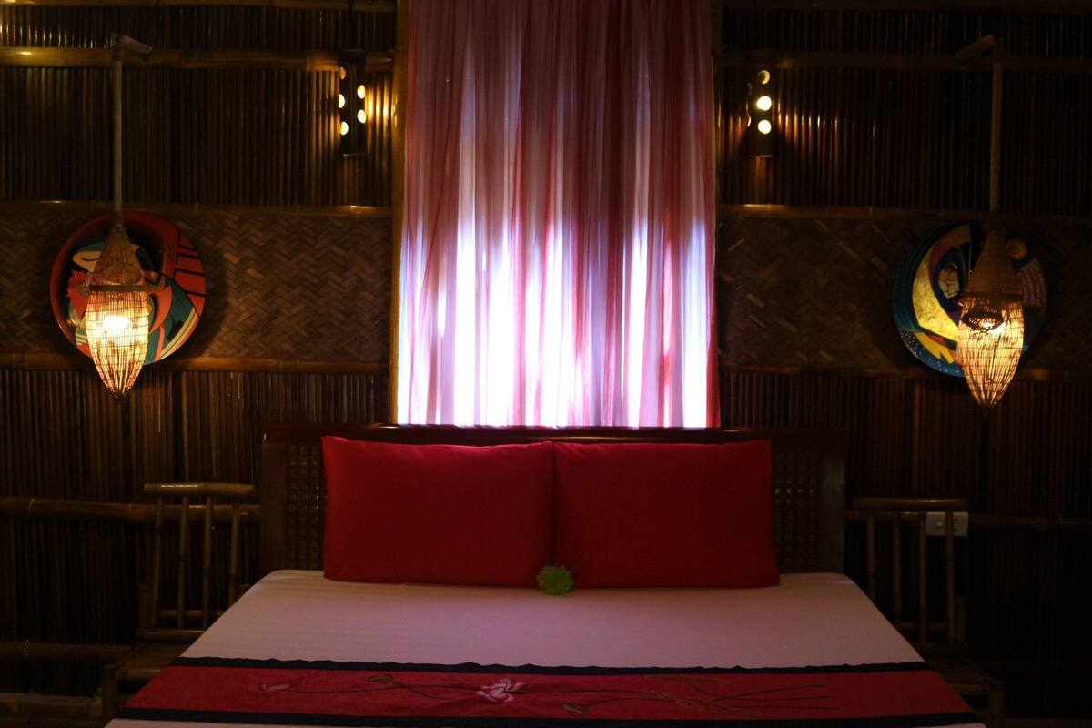 Ein Zimmer mit einem Bett, roten Kissen und dekorativen Wandleuchten.