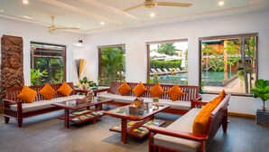 A spacious living area with a sofa set, coffee table, and a ceiling fan. - Khmer House Resort (Siem Reap)