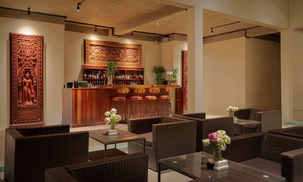 A bar area with a wooden counter, bar stools, and a decorative wall panel.