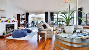 A modern living room with a fireplace, seating area, and a view of a mountainous landscape. - Amazing Queenstown Guesthouse (Queenstown)
