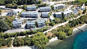 An aerial view of a coastal residential area with modern apartment buildings, a clear beach, and a pier. - Amazing Queenstown Guesthouse (Queenstown)