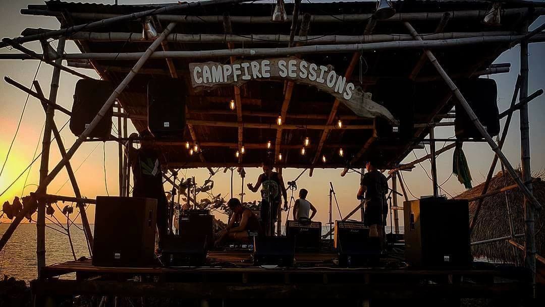 Eine Bühne mit einem Schild, auf dem 'CAMPFIRE SESSIONS' steht, vor einem Sonnenuntergang.