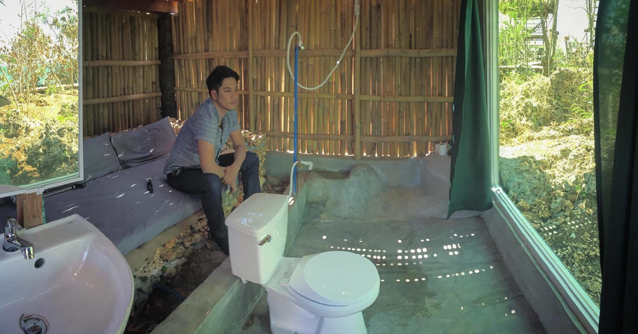 A rustic bathroom with a wooden wall, a bathtub, a sink, and a toilet.