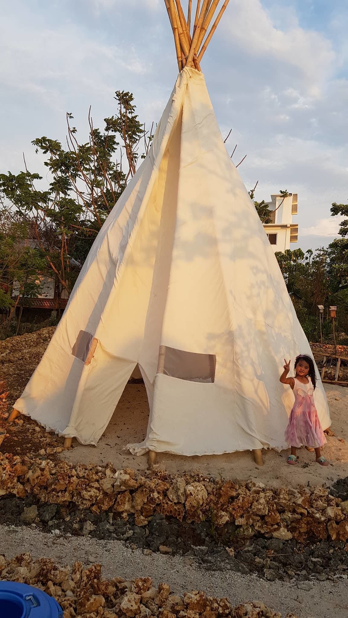 En stor hvid tipi med et barn foran.