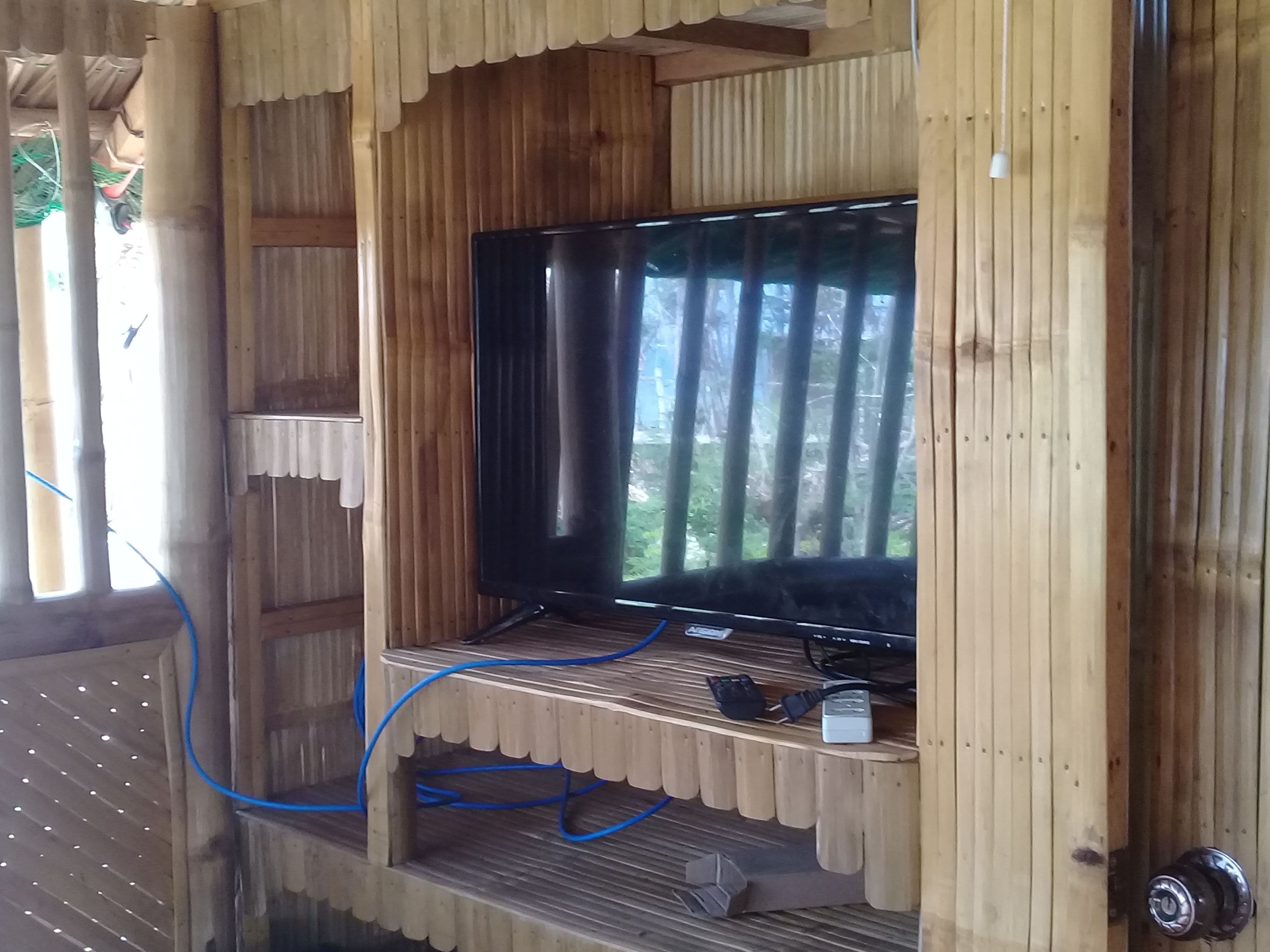 Een houten tv-meubel met een flatscreen televisie, een stopcontact en een kabelmanagement systeem.