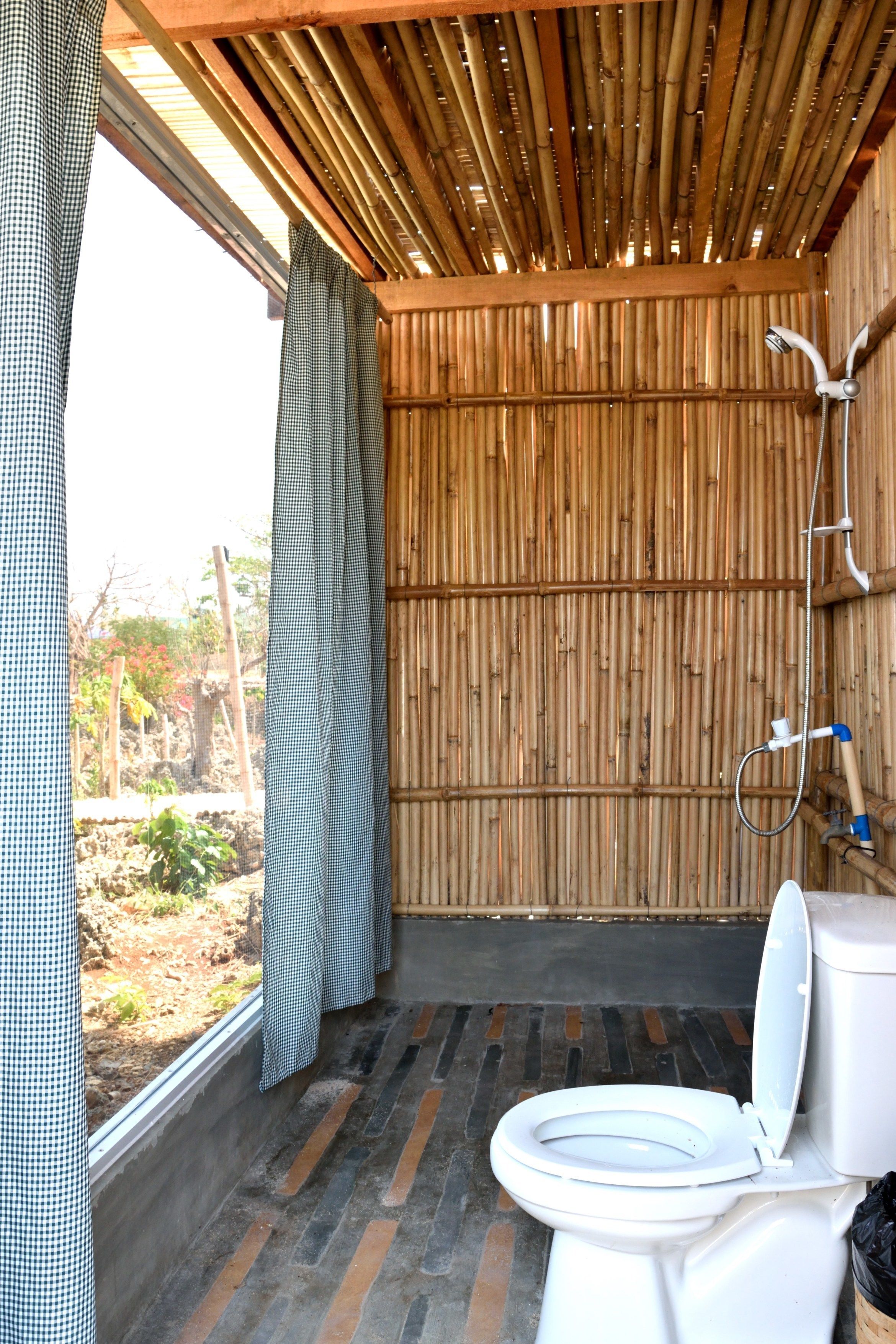 A bathroom with a bamboo ceiling, a toilet, and a shower.