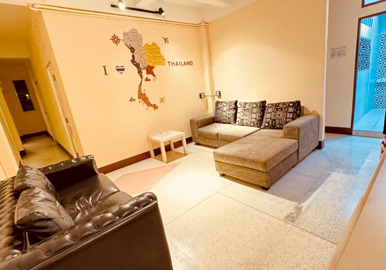 A living room with a sofa, a small table, and a map of Thailand on the wall.