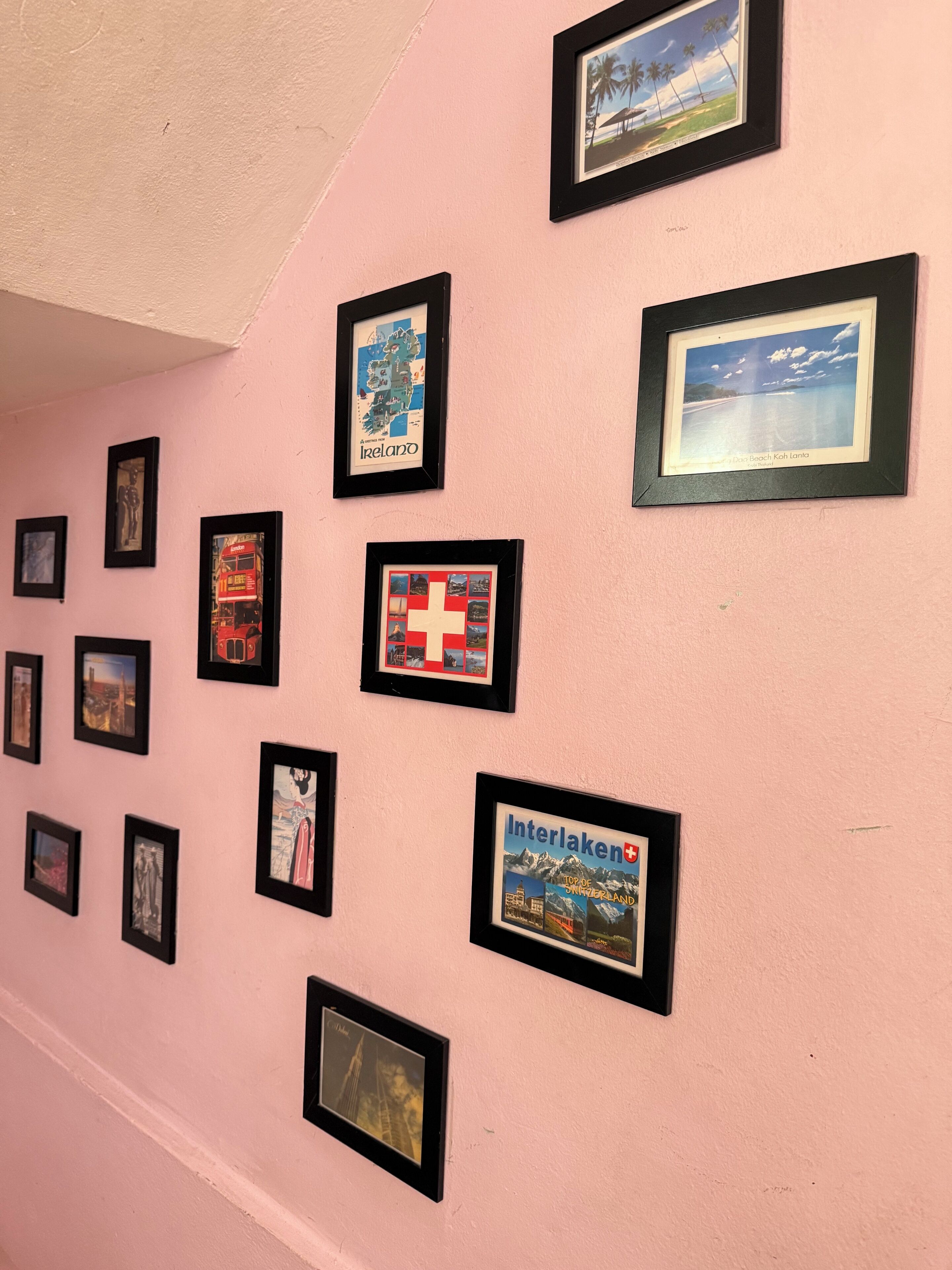 A wall with multiple framed pictures, including a map of Ireland, a Swiss flag, and a picture of a mountain range.
