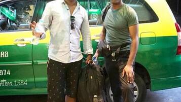 Two individuals standing in front of a green and yellow vehicle with visible text and numbers on the side.