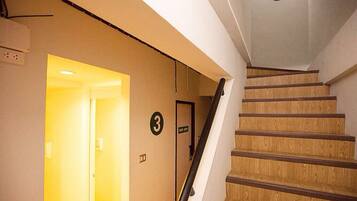 Una escalera de madera con barandilla, que conduce a un rellano con una puerta marcada con el número 3.