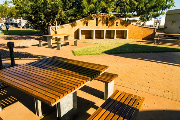 A picnic area with benches and tables, surrounded by a brick wall and greenery.