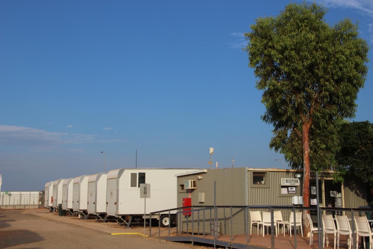 A row of mobile homes with a reception area and chairs in front.