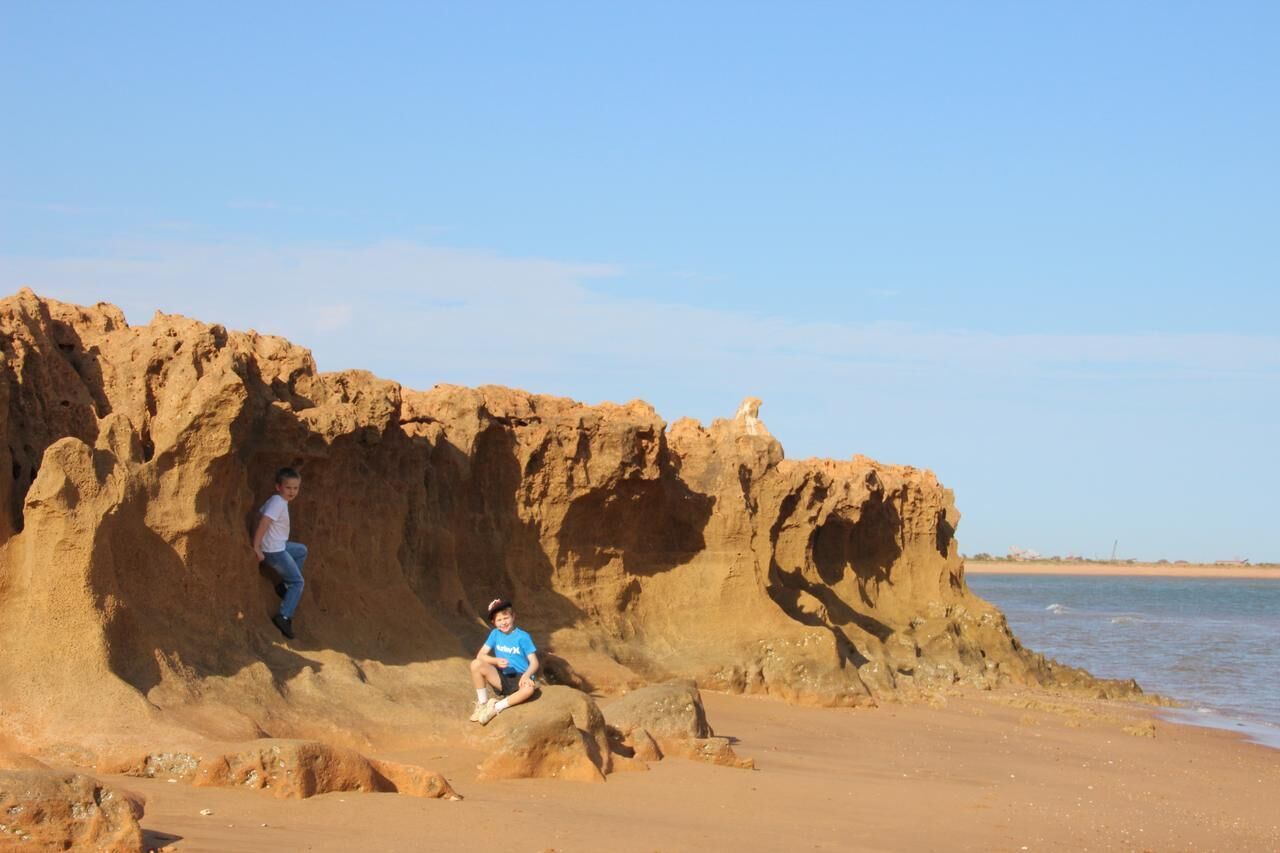 Una playa arenosa con formaciones rocosas y un cielo despejado.