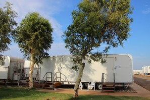 Várias caravelas brancas estacionadas num parque de estacionamento, com árvores ao primeiro plano.