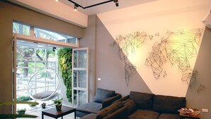 A modern living room with a sectional sofa, a small coffee table, and a hanging plant. - ManMan (Hualien City)