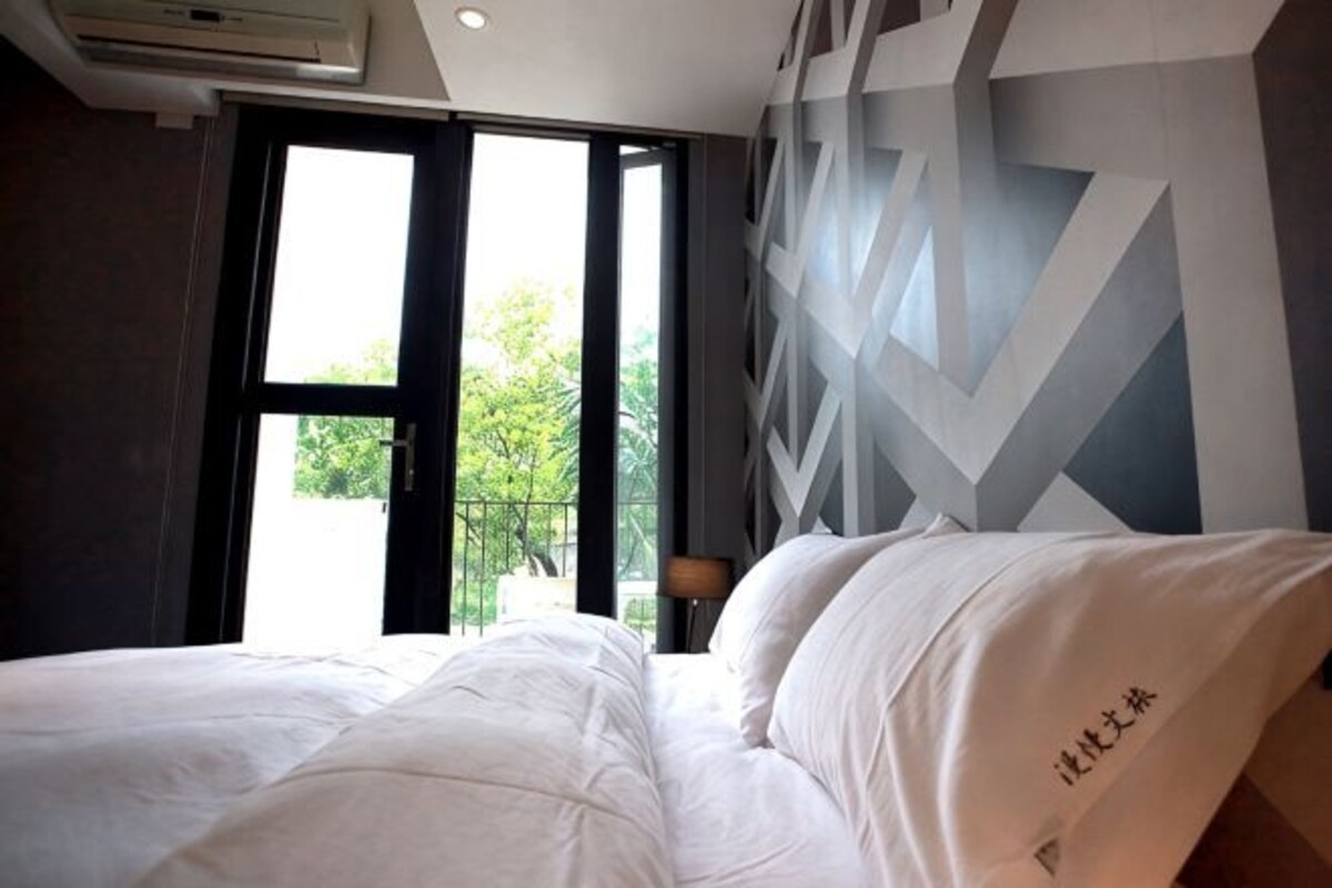 Una habitación de hotel con cama, ventana y pared con diseños geométricos.
