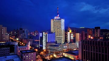 A high-rise hotel with a distinctive spire, surrounded by other buildings and city lights.