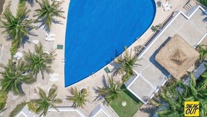 An aerial view of a heart-shaped swimming pool surrounded by palm trees and lounge chairs. - Baan Aom Kod Kun Kao (Suan Phueng)