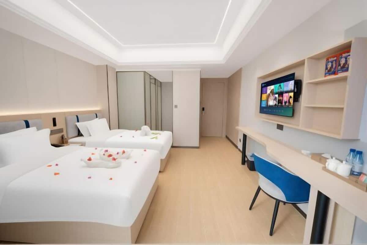 Une chambre d’hôtel moderne équipée de deux lits, d’un bureau, d’une chaise, d’une télévision et d’un miroir.