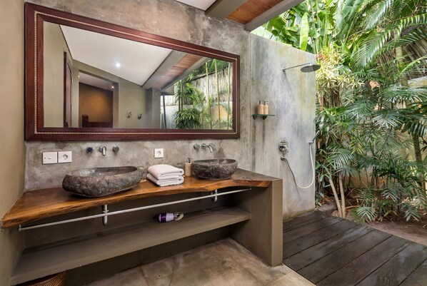 Une salle de bain avec un grand miroir, deux vasques en pierre et une douche.