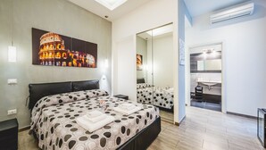 A modern hotel room with a large bed, a desk, and a bathroom visible through an open door. - Domus Alberti (Rome)