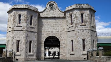 A historic stone building with a clock tower, arched entrance, and barred gates.