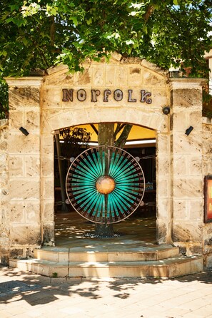 A stone archway with the word "NORFOLK" and a large decorative wheel structure beneath it.