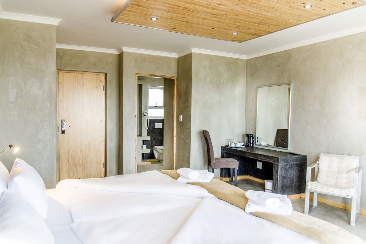Una habitación de hotel moderna con una cama grande, un tocador con espejo y una zona de estar.