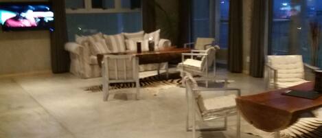 A modern living room with a sofa set, a dining table, and a zebra rug.