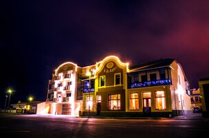 Un edificio de varios pisos con señalización e iluminación, y ventanas, que sugiere ser un hotel o establecimiento comercial.