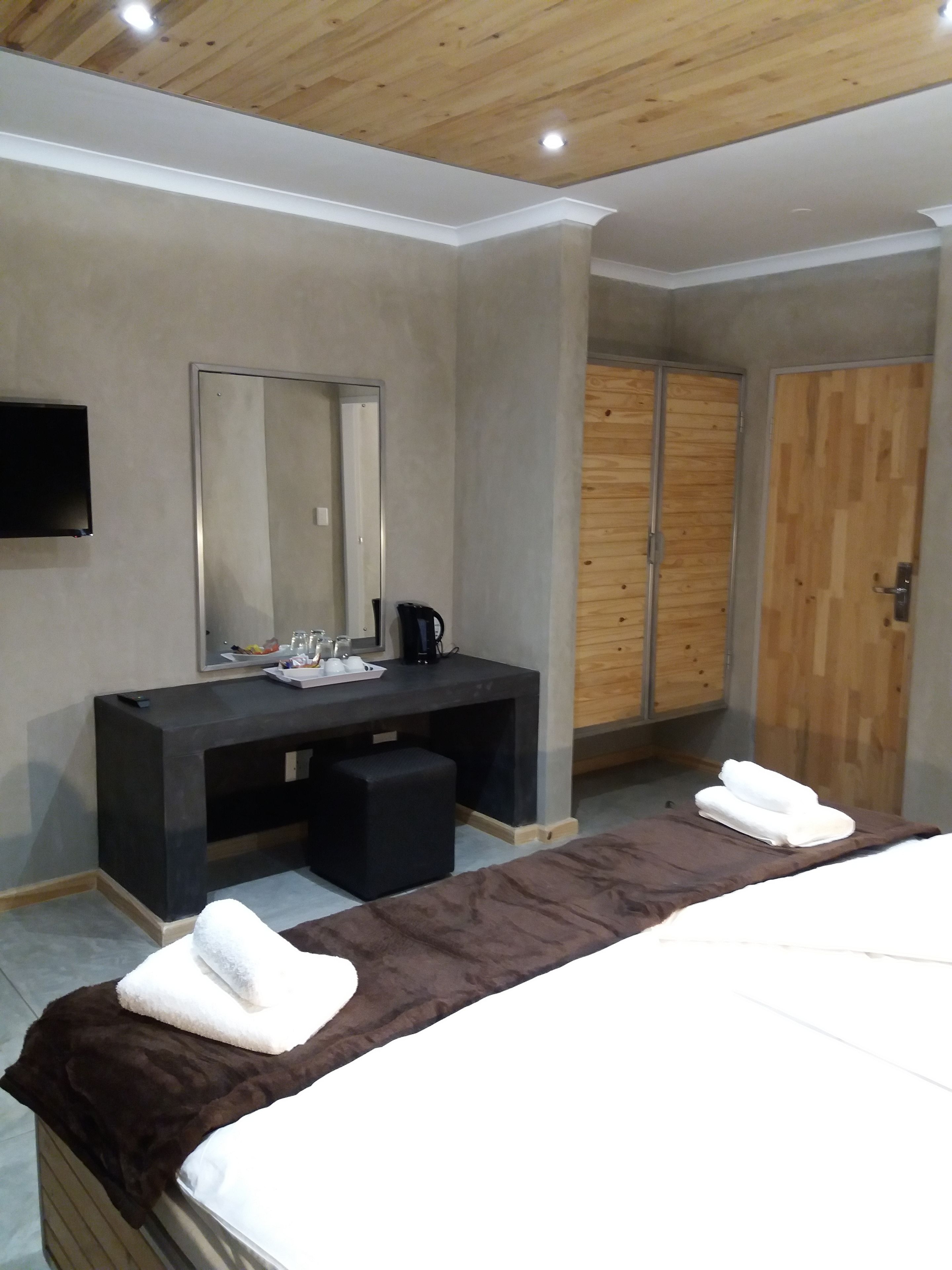 Une chambre d’hôtel moderne dotée d’un grand lit, d’un bureau avec un miroir, d’une télévision à écran plat et d’une armoire.