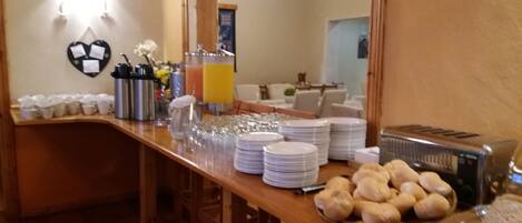 A buffet setup with plates, cups, and a toaster.