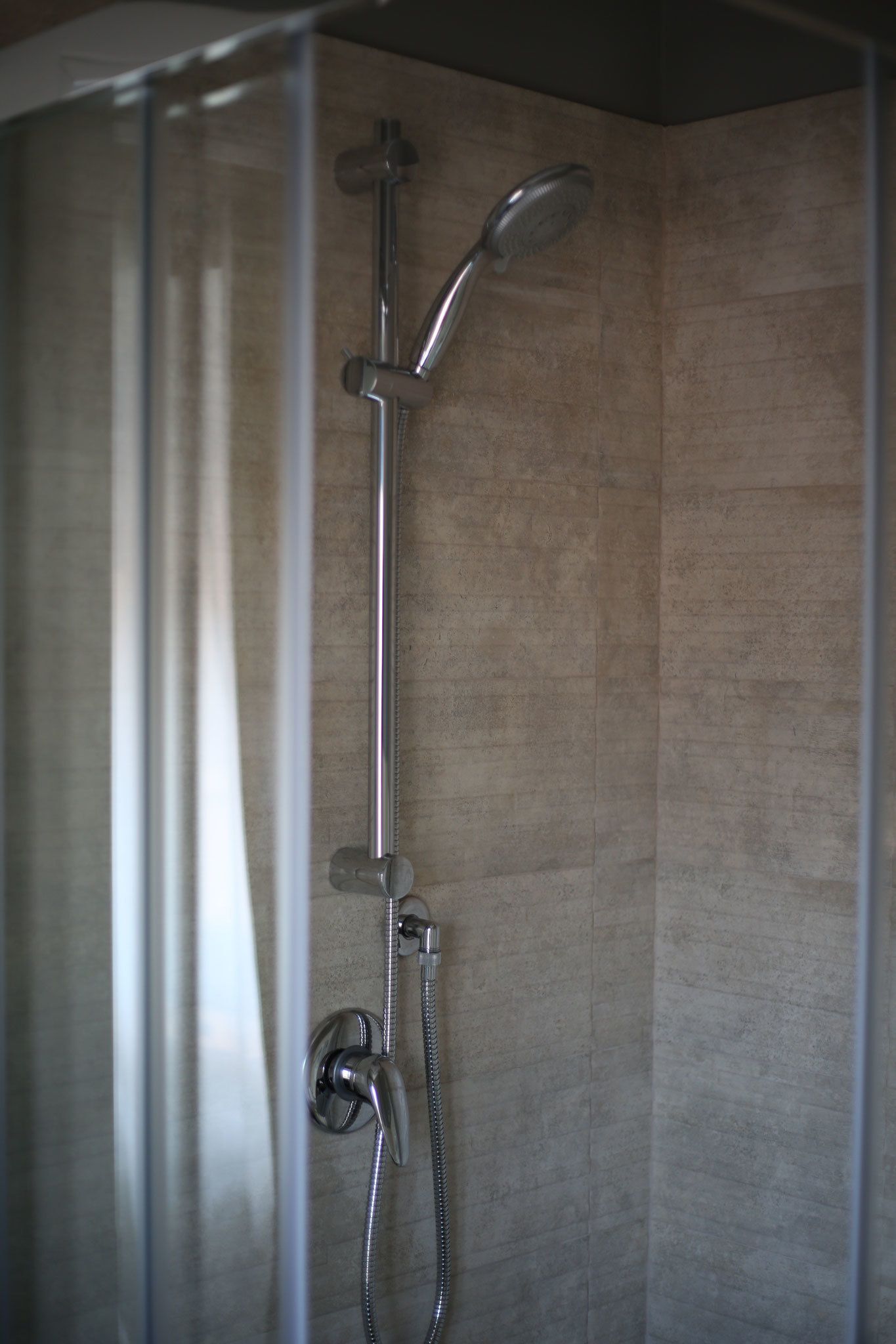 A shower with a handheld showerhead and a wall-mounted faucet.