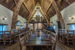 A long dining table with wooden chairs, a wooden ceiling, and a staircase leading to an upper level. - Craven Shepherd Huts (Skipton)