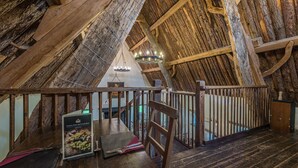 A rustic wooden interior with a high ceiling, wooden beams, and a staircase. - Craven Shepherd Huts (Skipton)