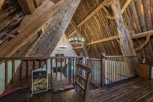 Un interior rústico de madera con techo alto, vigas de madera y una escalera.