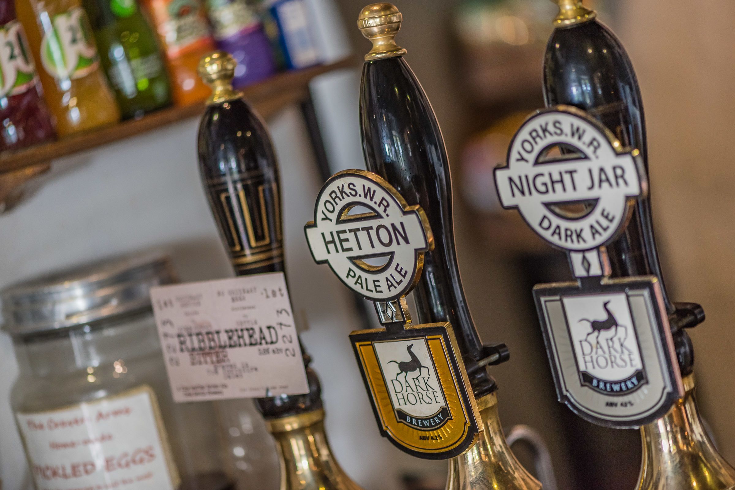 Gros plan sur des robinets à bière avec des étiquettes indiquant « Yorks W.R. Hepton Pale Ale » et « Night Jar Dark Ale ».