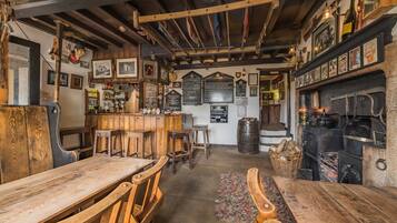 A rustic pub interior with wooden furniture, a bar area, and a traditional fireplace.