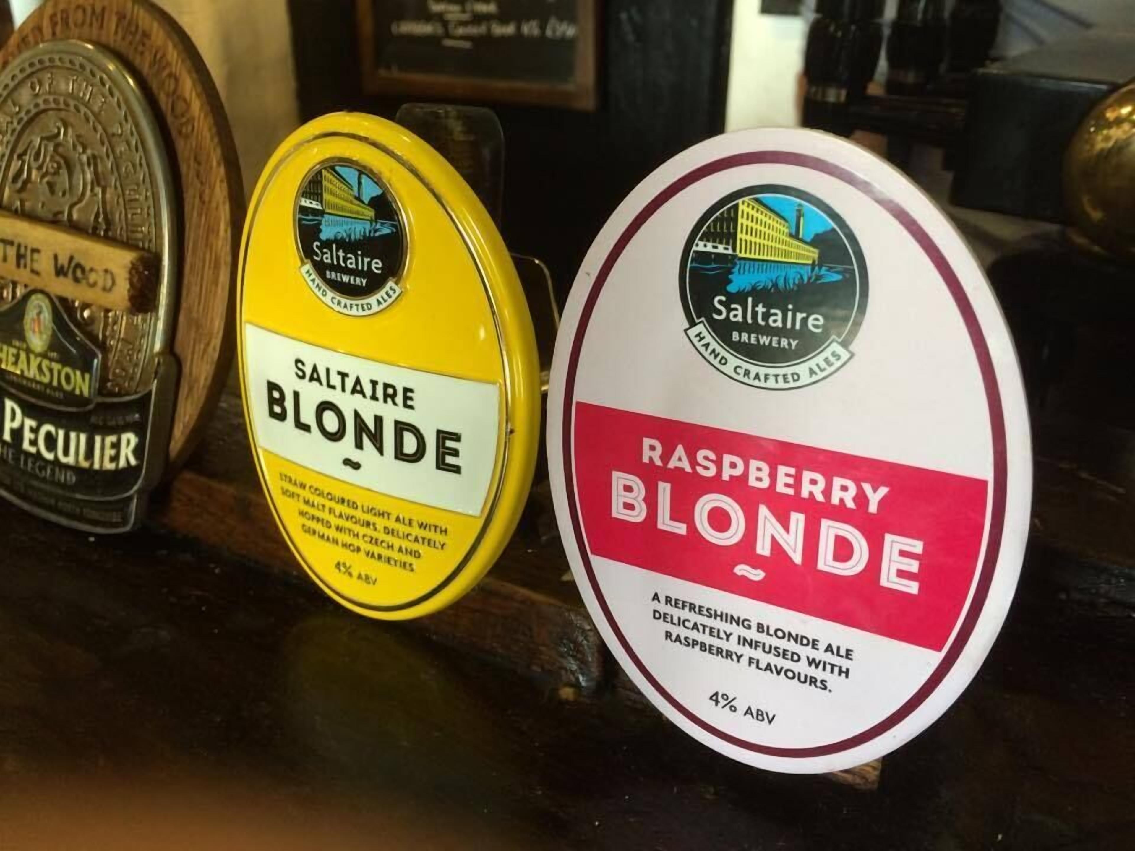 Three bottles of Saltaire Blonde ale, one with a yellow label and the other with a red label, both from Saltaire Brewery.