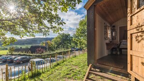 A wooden cabin with a view of a parking area and a rural landscape. - Craven Shepherd Huts (Skipton)