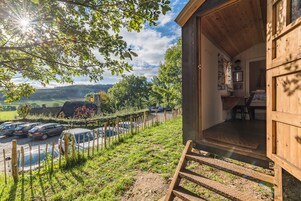 Una cabaña de madera con vista a un estacionamiento y un paisaje rural.