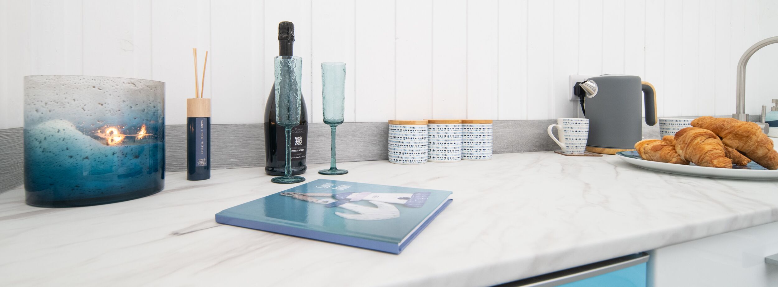 Una encimera de cocina con una vela azul, un candelabro azul, una caja para velas azules, una caja para velas azules, una caja para velas azules, una caja para velas azules, una caja para velas azules, una caja para velas azules, una caja para velas azules, una caja para velas azules, una caja para velas azules, una caja para velas azules, una caja para velas azules, una caja para velas azules, una caja para velas azules, una caja para velas azules, una caja para velas azules, una caja para velas azules, una caja para velas azules, una caja para velas azules, una caja para velas azules, una caja para velas azules, una caja para velas azules, una caja para velas azules, una caja para velas azules, una caja para velas azules, una caja para velas azules, una caja para velas azules, una caja para velas azules, una caja para velas azules, una caja para velas azules, una caja para velas azules, una caja para velas azules, una caja para velas azules, una caja para velas azules, una caja para velas azules, una caja para velas azules, una caja para velas azules.