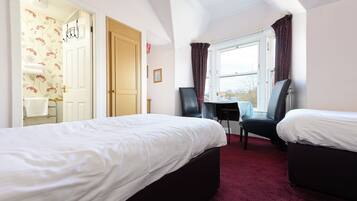 Une chambre d’hôtel avec deux lits, un bureau et une fenêtre avec des rideaux.