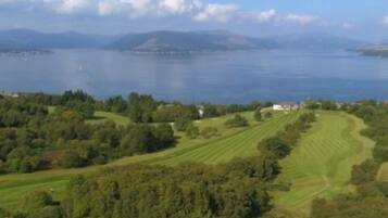 Un parcours de golf offrant une vue sur un lac et des montagnes lointaines.