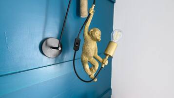 Un luminaire mural représentant un singe tenant une lampe, et raccordé à une source d’alimentation.