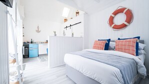 Un dormitorio moderno con una cama grande, una kitchenette pequeña y vistas al exterior.