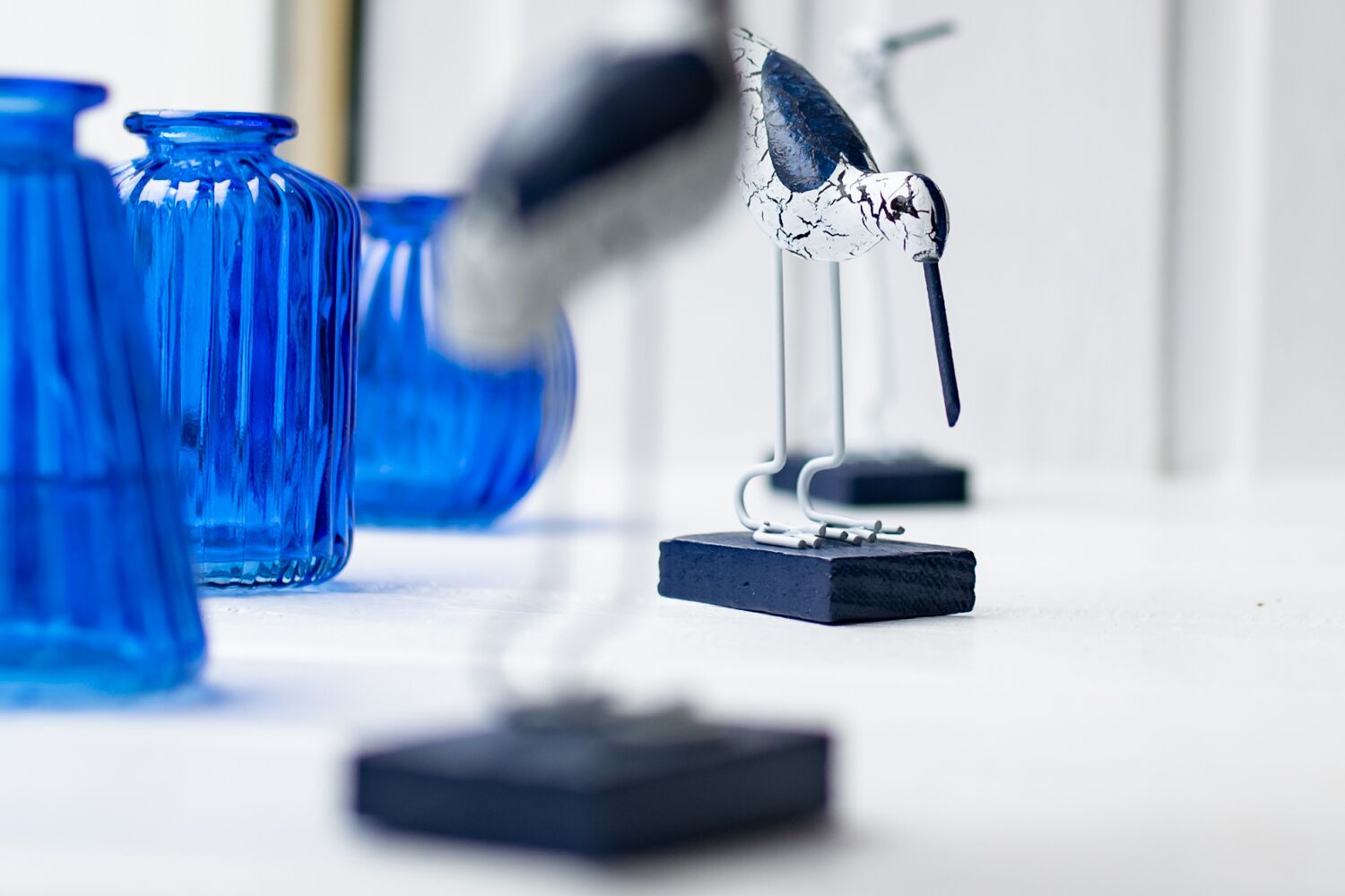 A bird perched on a stand with a blue object in the background.